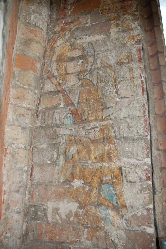 Wschodnia ściana tarczowa chóruEwangelista Łukasz, siedzący z otwartą księgą w lewej ręce i prawdopodobnie laską malarską w prawej. Nad nim tzw. wimperga z pinaklami i wieżyczkami na kalenicy, typowe gotyckie zwieńczenie portali, okien, szczytów, a także herbów.